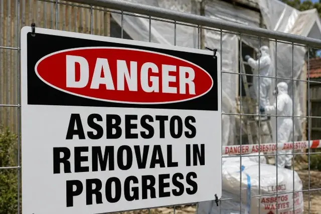 Asbestos removal warning sign on a temporary work-site barrier